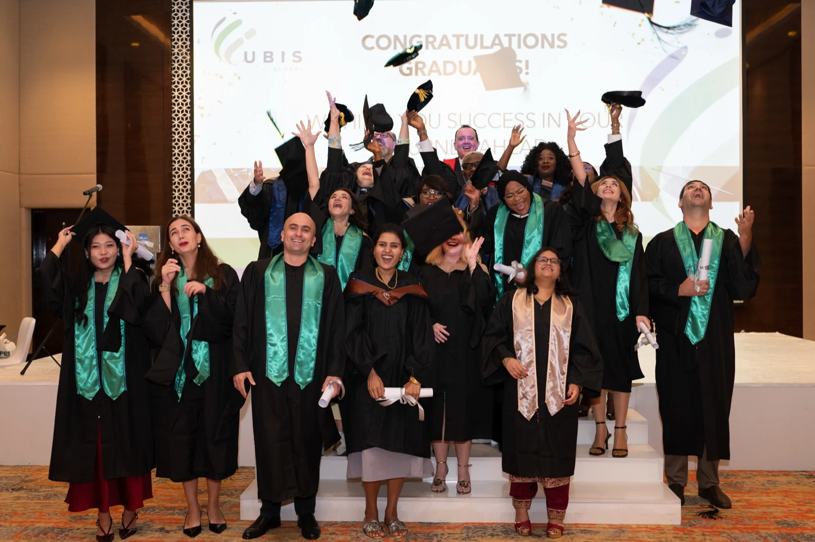 UBIS graduates throwing their caps at a graduation ceremony