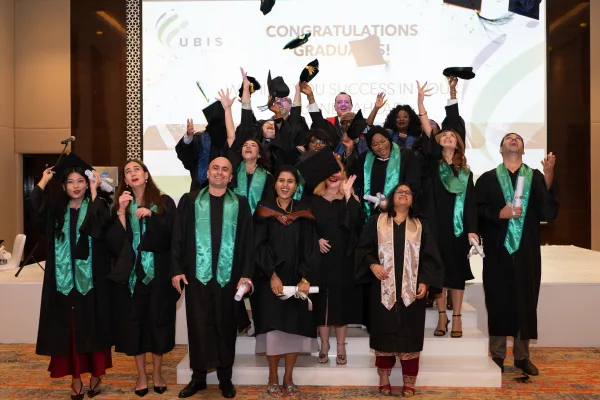 UBIS graduates throwing their caps at a graduation ceremony