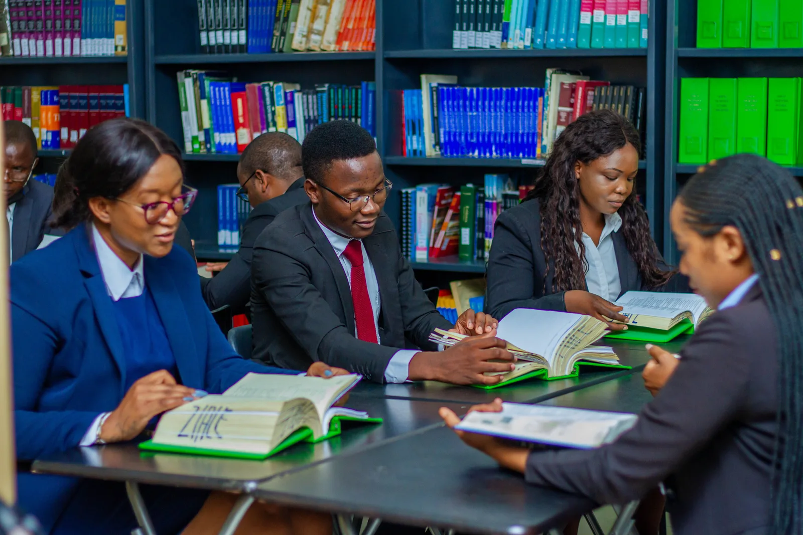 A diverse group of adult students studies together at a library table with books.