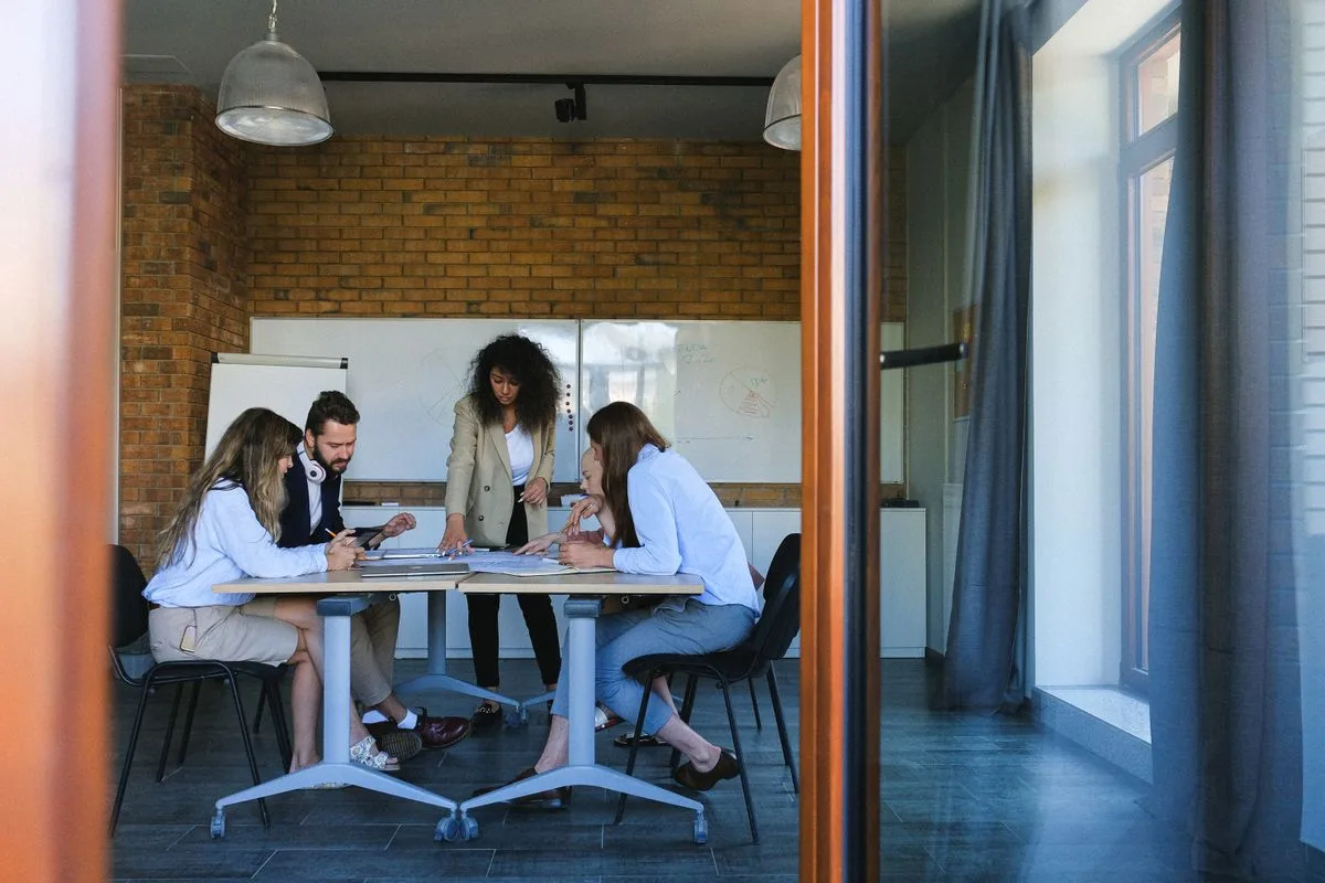 A diverse group of colleagues discussing documents during a meeting in a modern conference room.