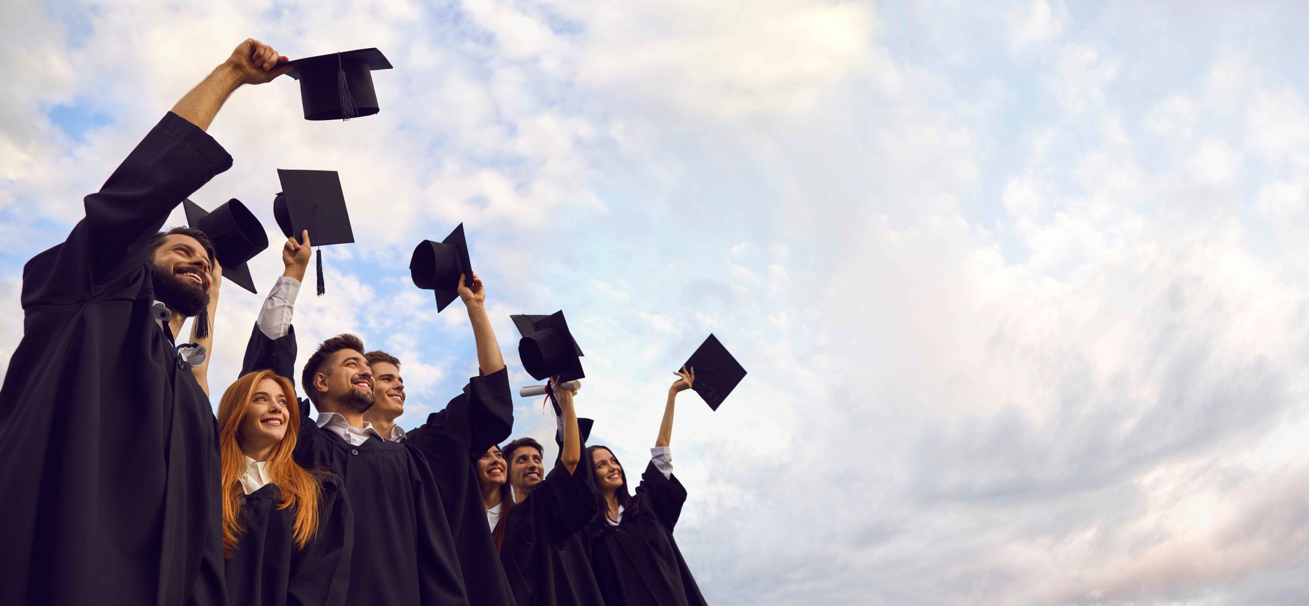 group of students graduating outside and throwing their caps in the air